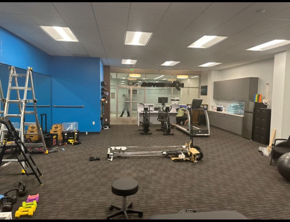 Modern fitness studio interior with equipment, including weights, exercise bikes, and mirrors.