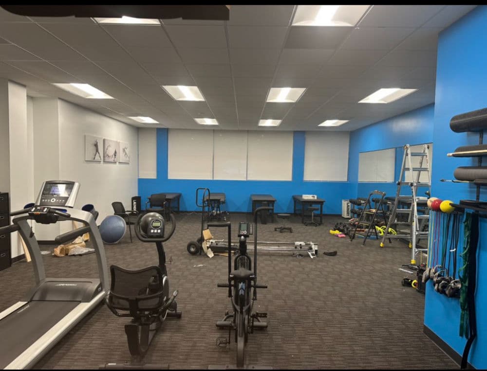 Modern gym interior with cardio equipment, free weights, and exercise mats.