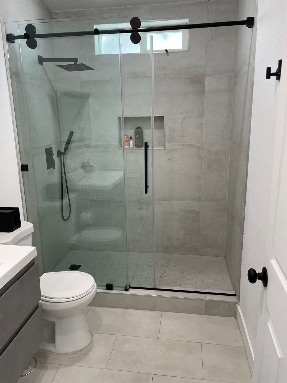 Modern bathroom featuring a glass shower enclosure, sleek fixtures, and neutral tile design.