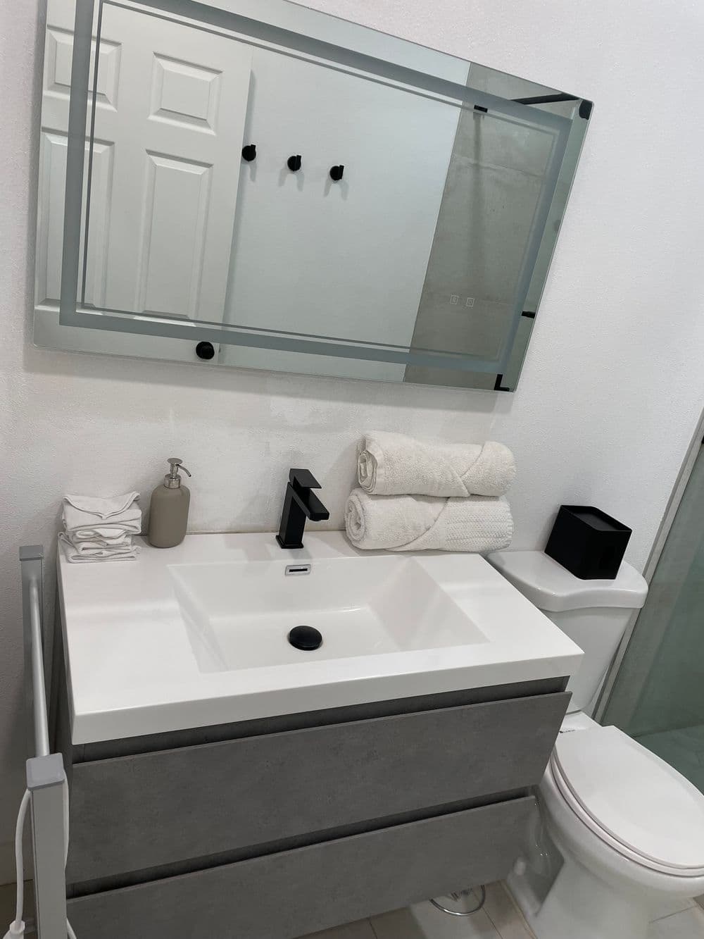Modern bathroom vanity with sink, towels, and mirror in a stylish, minimalistic design.