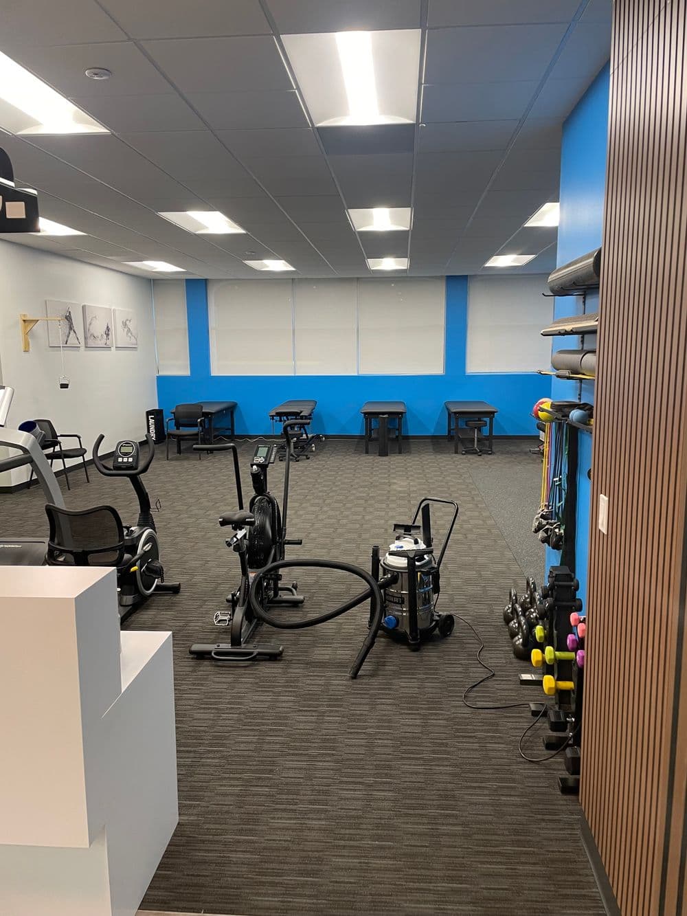 Modern fitness gym interior featuring exercise equipment and workout space with blue accents.