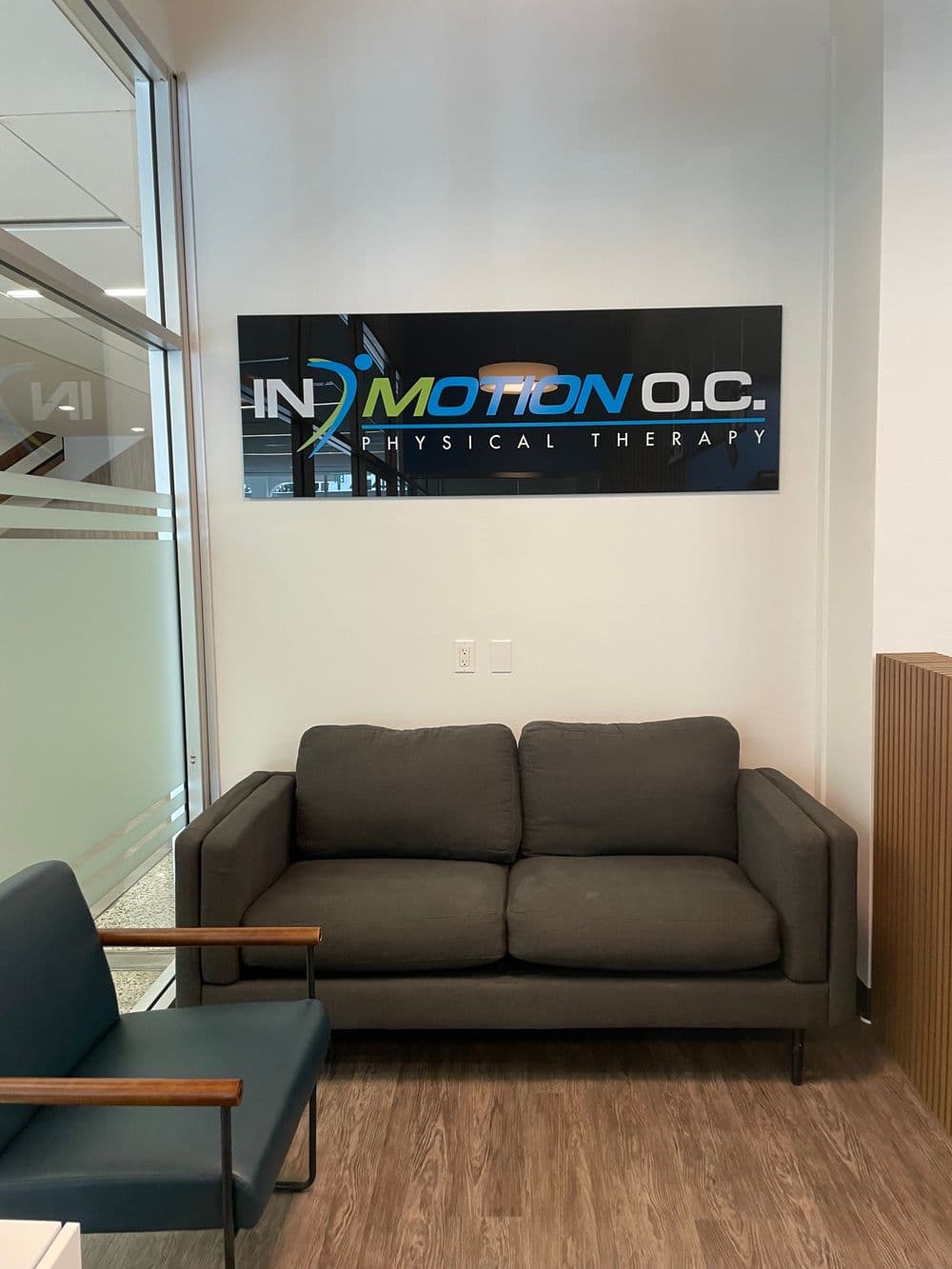 InMotion O.C. Physical Therapy clinic interior with modern seating area and wall sign.