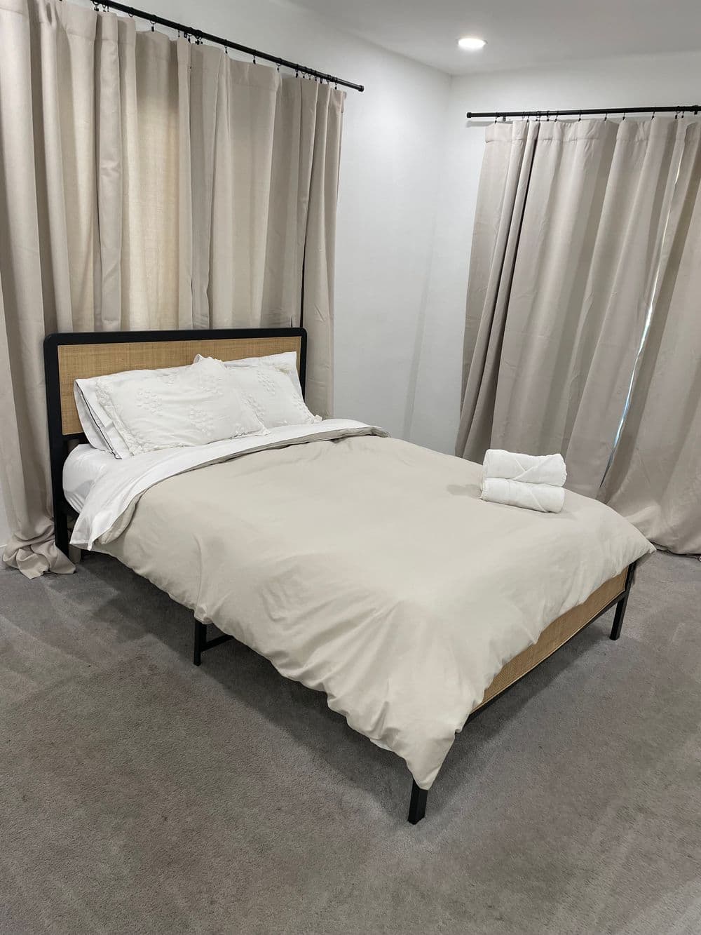 Minimalistic bedroom with neutral bedding, a cozy quilt, and neatly arranged towels.