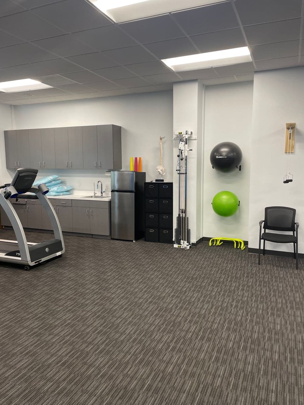 Physical therapy clinic with exercise equipment, storage, and rehabilitation tools for patients.